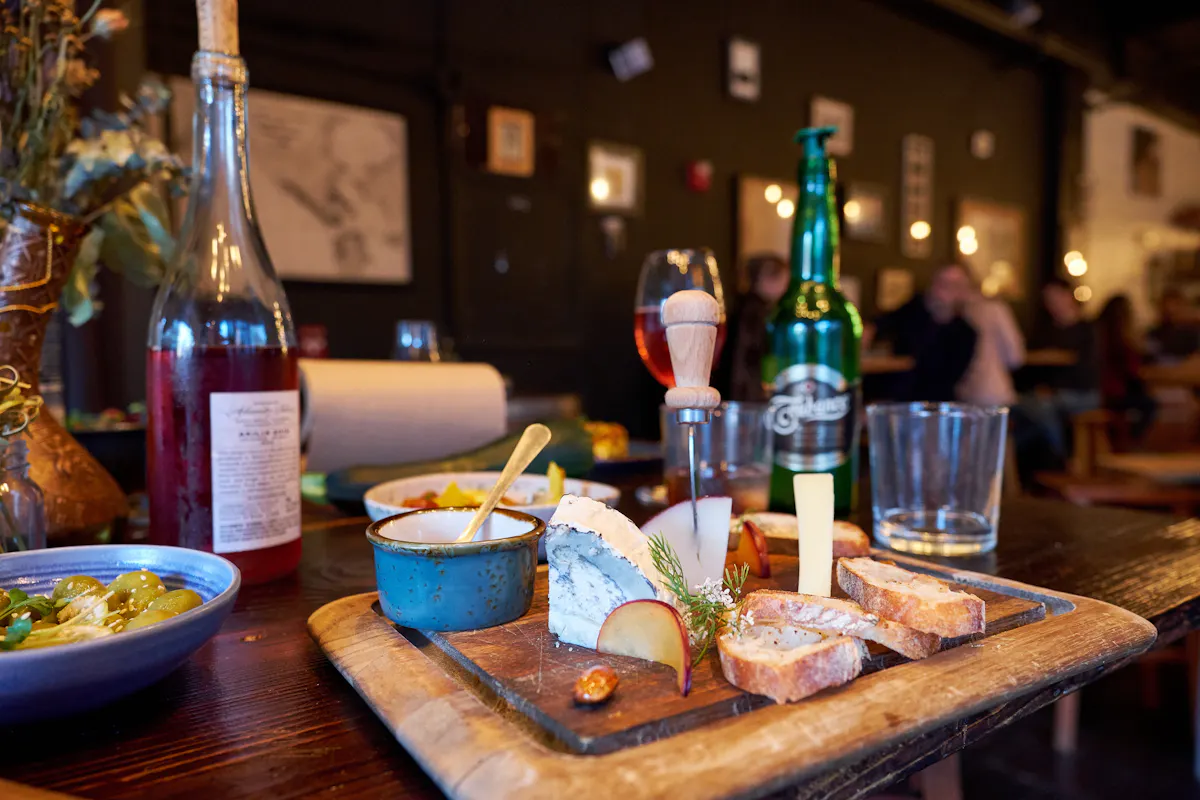 a bottle of wine sitting on top of a wooden table with snacks and glasses